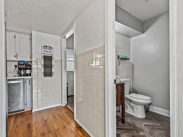 interior space with tile walls, a textured ceiling, and white cabinets