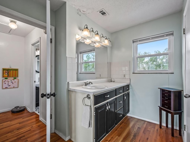 bathroom featuring hardwood / wood-style flooring, vanity, tasteful backsplash, and a textured ceiling