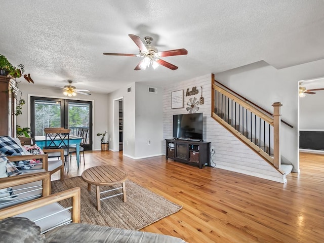 living room featuring ceiling fan, hardwood / wood-style flooring, and a textured ceiling