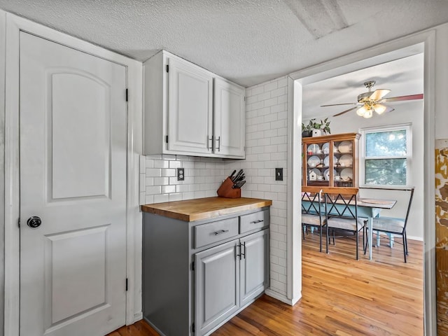 kitchen with white cabinetry, backsplash, a textured ceiling, wood counters, and light wood-type flooring