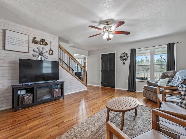 living room with hardwood / wood-style flooring, a textured ceiling, and ceiling fan