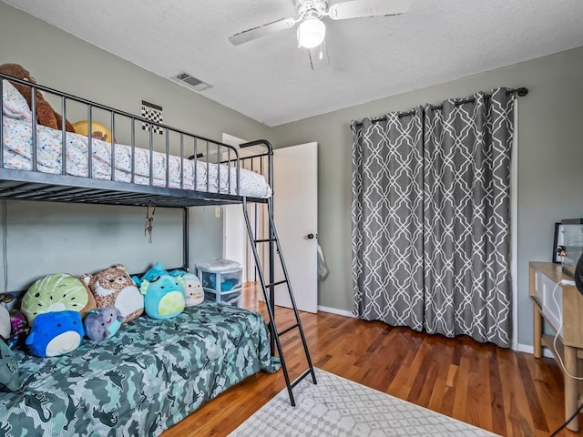 bedroom with hardwood / wood-style floors, a textured ceiling, and ceiling fan