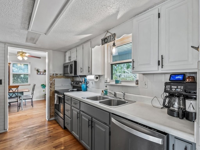 kitchen featuring appliances with stainless steel finishes, sink, white cabinets, and light hardwood / wood-style flooring