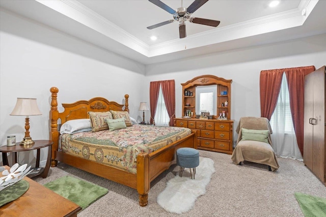 carpeted bedroom with crown molding, a tray ceiling, and ceiling fan