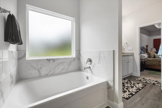 bathroom with vanity, a bath, and hardwood / wood-style floors