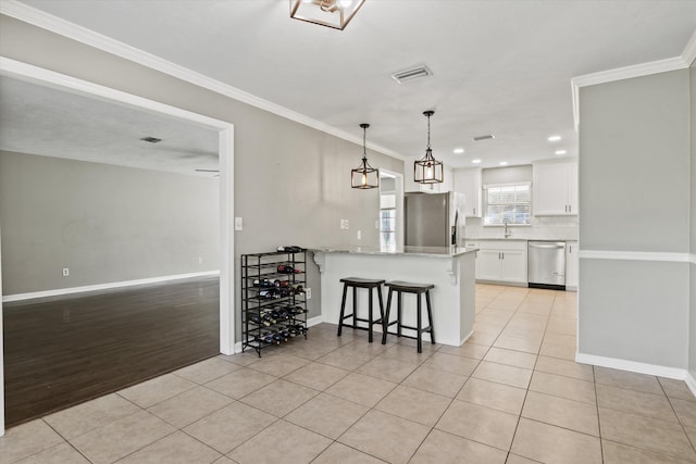 kitchen with appliances with stainless steel finishes, white cabinets, backsplash, a peninsula, and light tile patterned flooring