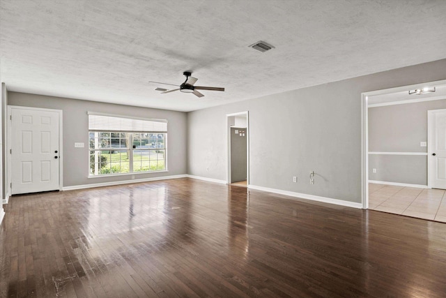 unfurnished living room with ceiling fan, hardwood / wood-style flooring, visible vents, and baseboards