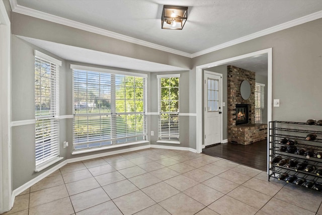 interior space featuring baseboards, crown molding, tile patterned flooring, and a brick fireplace