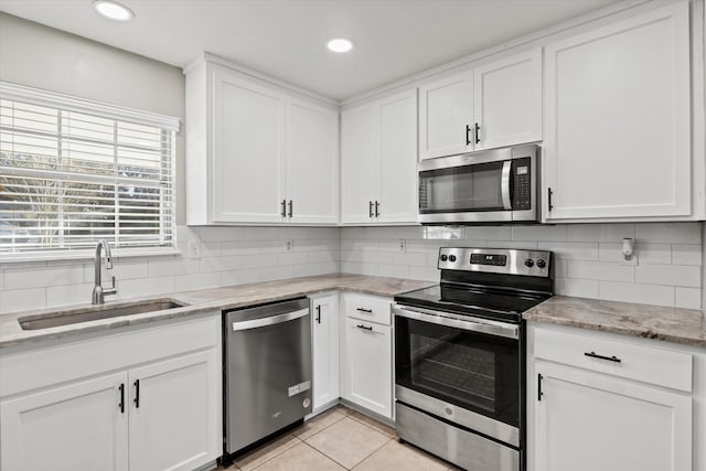 kitchen featuring a sink, appliances with stainless steel finishes, decorative backsplash, and white cabinetry