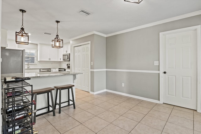 kitchen with stainless steel appliances, ornamental molding, backsplash, a kitchen bar, and white cabinetry