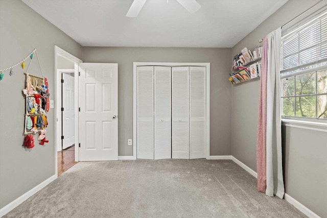 unfurnished bedroom featuring baseboards, ceiling fan, a closet, and carpet flooring