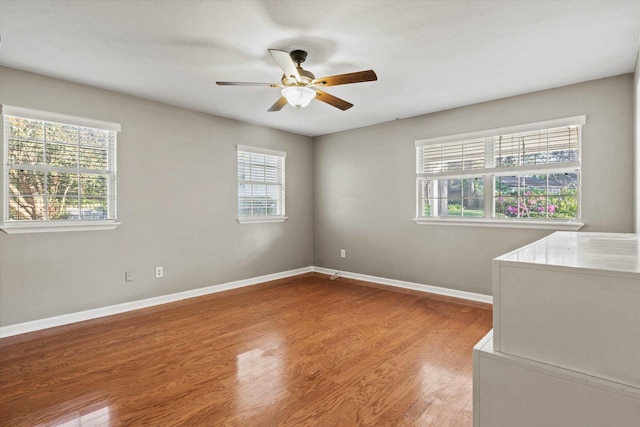 empty room with a ceiling fan, light wood finished floors, and baseboards