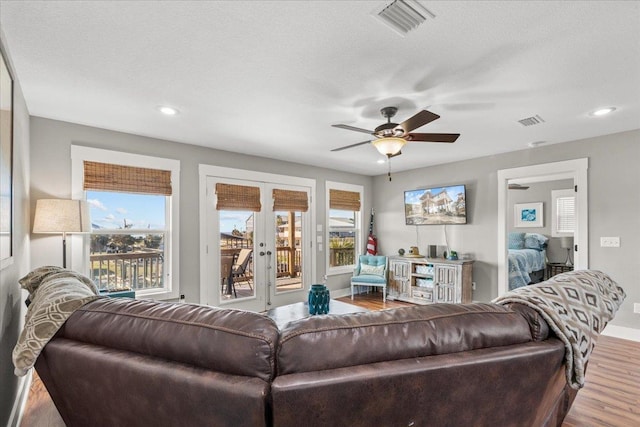 living room with plenty of natural light, hardwood / wood-style floors, ceiling fan, and french doors