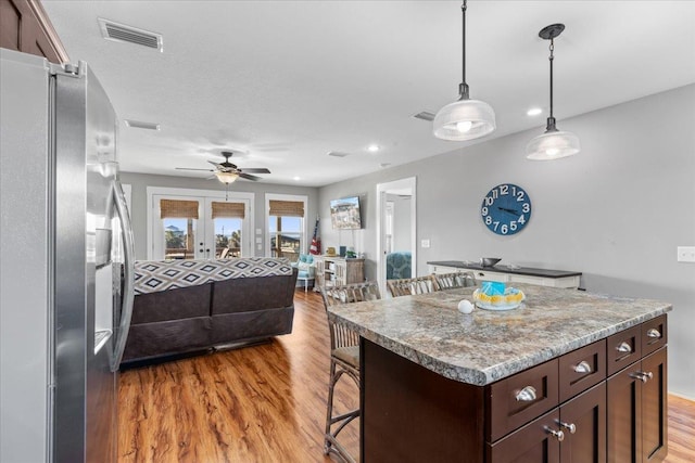 kitchen featuring hardwood / wood-style floors, dark brown cabinets, stainless steel fridge, and a kitchen island