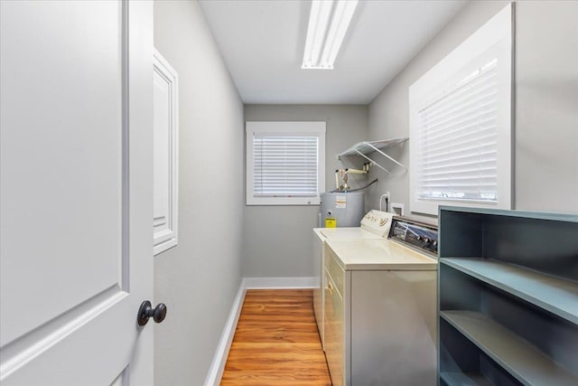 laundry area with water heater, washing machine and dryer, and light hardwood / wood-style floors