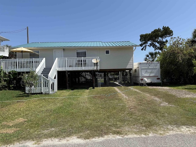 coastal home featuring a deck, a front lawn, stairway, and metal roof