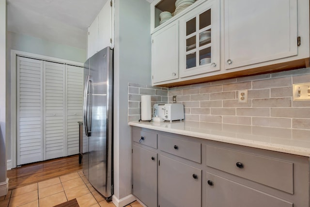 6509 Alan A Dale Trl, Tallahassee, FL 32309 - kitchen featuring freestanding refrigerator, decorative backsplash, glass insert cabinets, and light tile patterned flooring