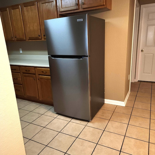 kitchen featuring freestanding refrigerator, light countertops, and light tile patterned flooring