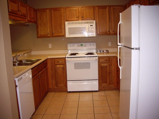 kitchen featuring white appliances, a sink, brown cabinetry, and light countertops