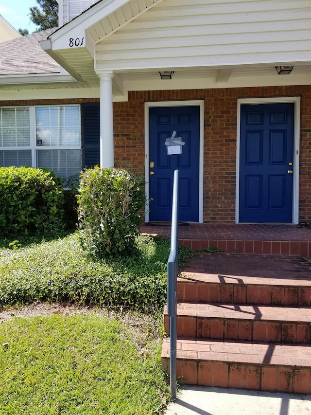 entrance to property featuring brick siding and covered porch