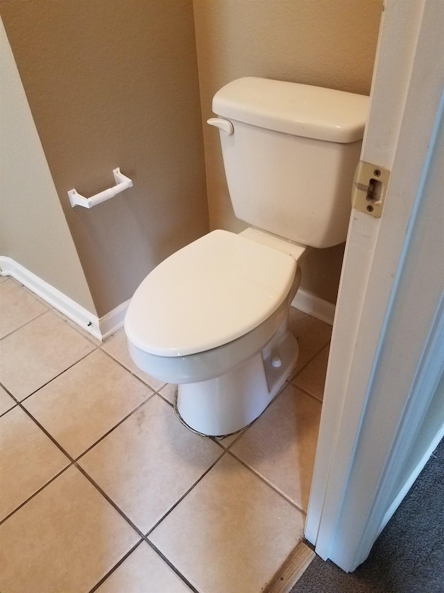 bathroom featuring toilet, baseboards, and tile patterned flooring