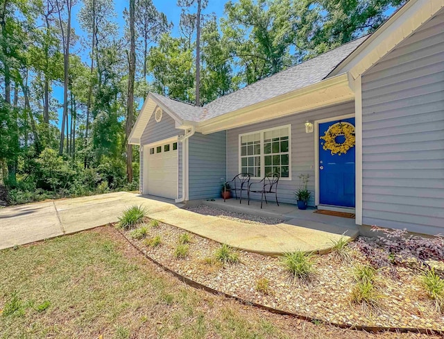 view of front of home with roof with shingles, covered porch, an attached garage, and concrete driveway