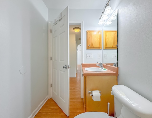 half bathroom featuring vanity, toilet, and wood finished floors