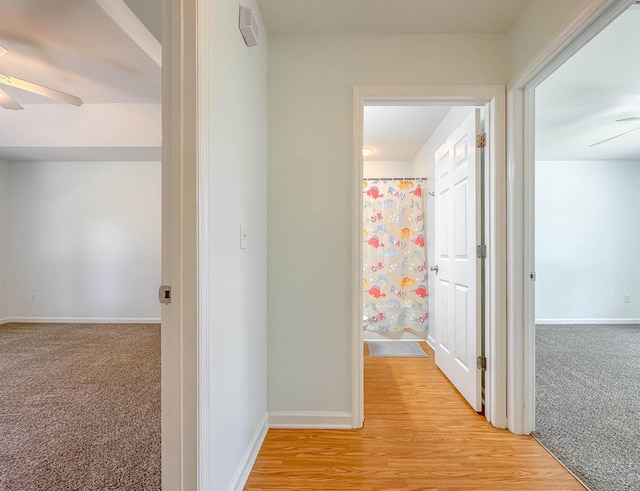 hall with baseboards and light colored carpet