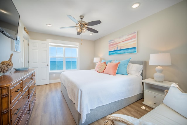 bedroom featuring a water view, ceiling fan, and light wood-type flooring