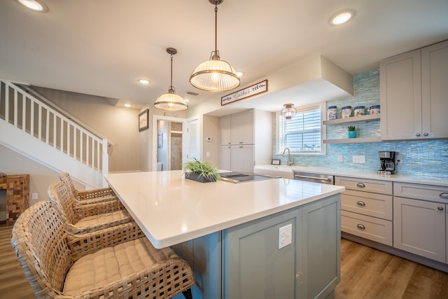 kitchen with gray cabinetry, dark hardwood / wood-style flooring, a center island, and a kitchen bar