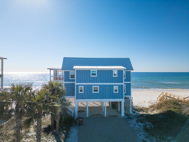 exterior space with a water view, a carport, a view of the beach, and a balcony