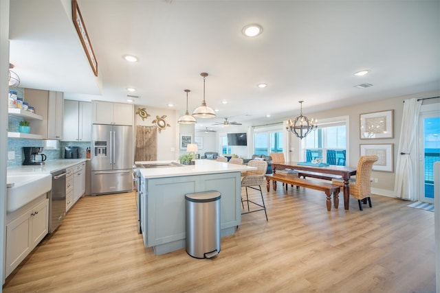 kitchen with a breakfast bar, decorative light fixtures, a center island, light wood-type flooring, and appliances with stainless steel finishes