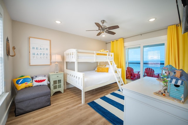 bedroom with light wood-type flooring, ceiling fan, and a water view