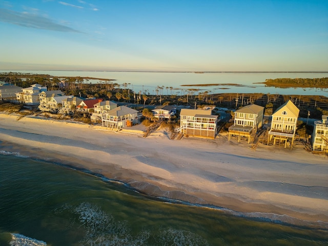 aerial view at dusk featuring a water view and a view of the beach