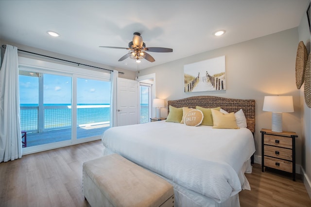 bedroom with hardwood / wood-style floors, access to outside, ceiling fan, and a water view