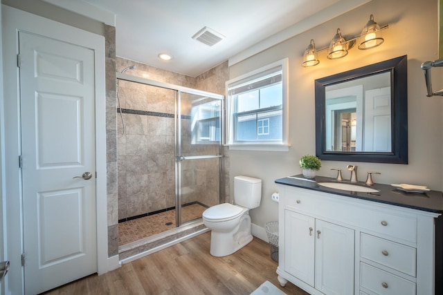 bathroom with an enclosed shower, vanity, hardwood / wood-style flooring, and toilet