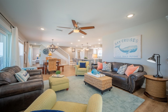 living room with wood-type flooring and ceiling fan with notable chandelier