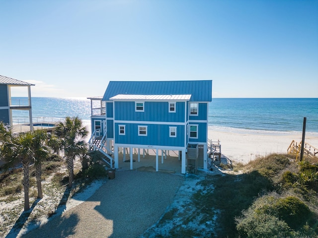 view of front facade featuring a view of the beach, a carport, and a water view