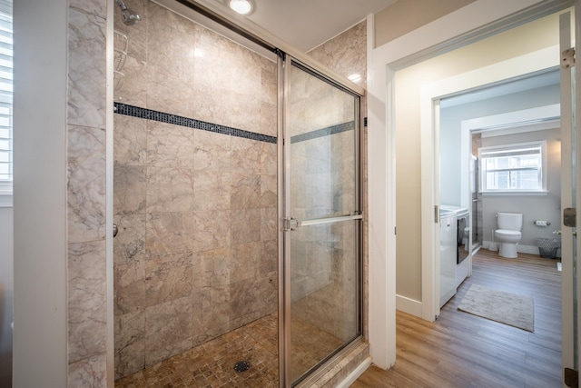 bathroom with hardwood / wood-style flooring, an enclosed shower, and toilet