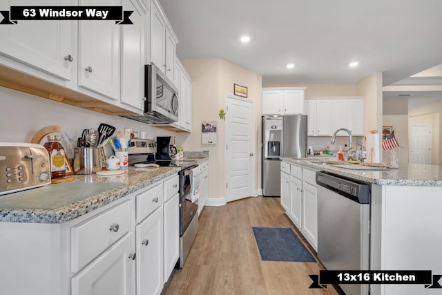 kitchen with appliances with stainless steel finishes, light hardwood / wood-style floors, white cabinetry, and sink