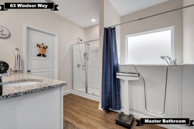 bathroom featuring hardwood / wood-style flooring, vanity, and walk in shower