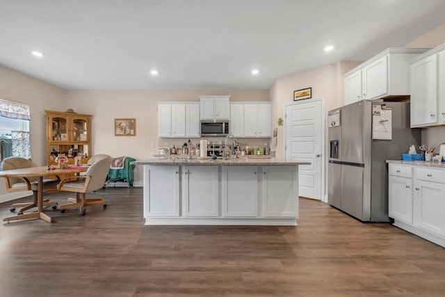 kitchen with light stone countertops, stainless steel appliances, and white cabinetry