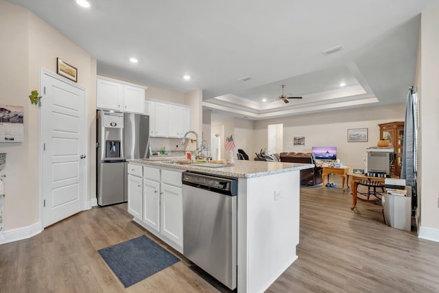 kitchen featuring appliances with stainless steel finishes, white cabinetry, and an island with sink