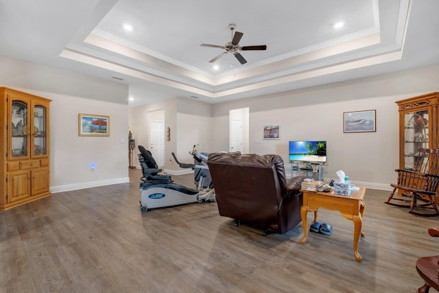 living room featuring a raised ceiling, crown molding, and hardwood / wood-style floors