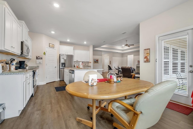 dining room featuring ceiling fan, sink, and light hardwood / wood-style flooring