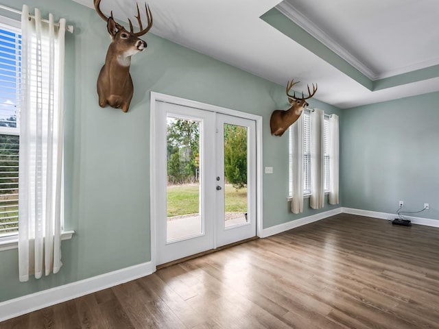 doorway with french doors, ornamental molding, a tray ceiling, and hardwood / wood-style floors