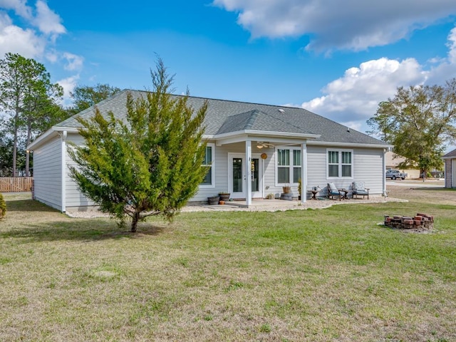 rear view of property featuring a yard, a patio area, and an outdoor fire pit