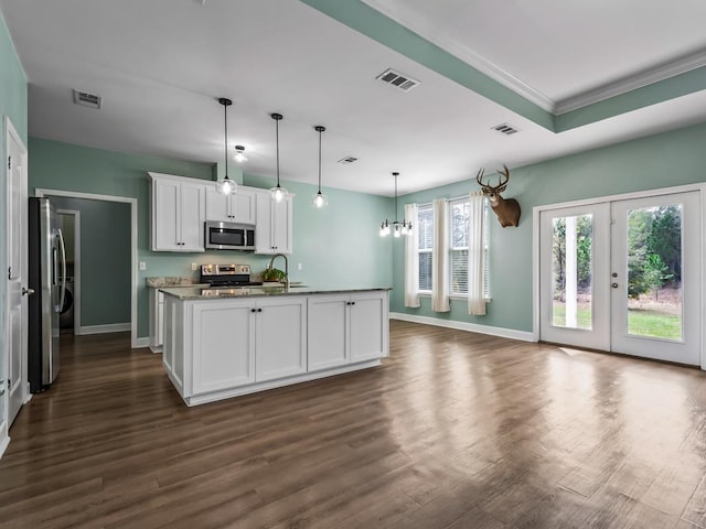 kitchen featuring pendant lighting, appliances with stainless steel finishes, a kitchen island with sink, dark hardwood / wood-style floors, and white cabinets