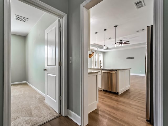 corridor featuring sink, light hardwood / wood-style flooring, and a raised ceiling