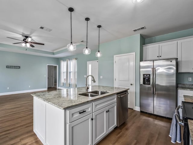 kitchen featuring sink, hanging light fixtures, appliances with stainless steel finishes, a kitchen island with sink, and white cabinets